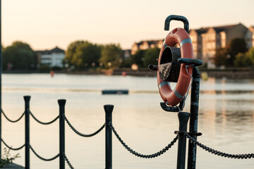 Orange lifebuoy hanging on a dock post at sunset © Jorge Elizaquibel