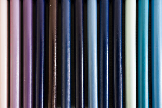 close-up of violet purple and blue colored pencils neatly lined up in pencil case, concept of creativity, drawing, education and art supplies