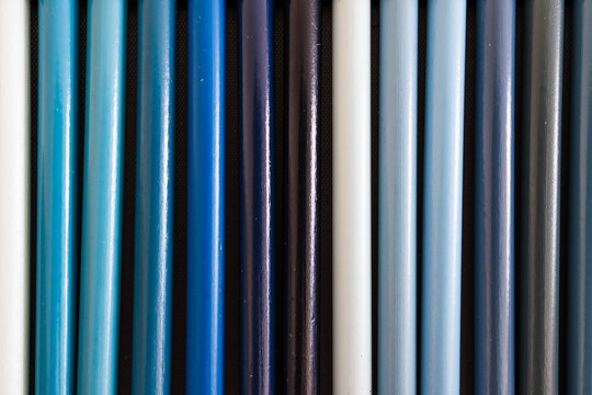 close-up of light and dark blue colored pencils neatly lined up in pencil case, concept of creativity, drawing, education and art supplies