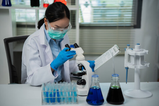 A female scientist is conducting chemical research in a laboratory, analyzing samples using test tubes and a microscope to drive advancements in biotechnology, medicine, microbiology, and healthcare.