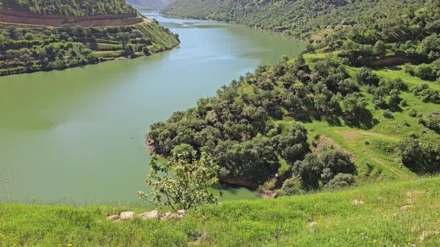 Emerald river curves through a dense green valley, bordered by trees and terraced hillsides beneath towering spring peaks and clear blue sky.
📍 Hawraman Takht, Kurdistan, Iran 