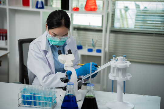 A female scientist is conducting chemical research in a laboratory, analyzing samples using test tubes and a microscope to drive advancements in biotechnology, medicine, microbiology, and healthcare.
