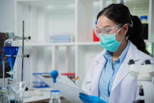 A female scientist is conducting chemical research in a laboratory, analyzing samples using test tubes and a microscope to drive advancements in biotechnology, medicine, microbiology, and healthcare.