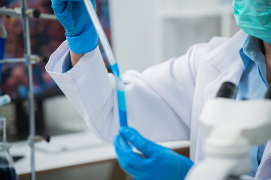 A female scientist is conducting chemical research in a laboratory, analyzing samples using test tubes and a microscope to drive advancements in biotechnology, medicine, microbiology, and healthcare.