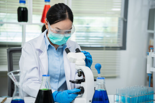 A female scientist is conducting chemical research in a laboratory, analyzing samples using test tubes and a microscope to drive advancements in biotechnology, medicine, microbiology, and healthcare.