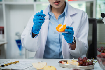 Scientist analyzing fresh organic fruit in laboratory, studying nutrition, vitamins, chemistry, genetics, microbiology, food safety, quality, agriculture, and health. © NANKHAMMAI