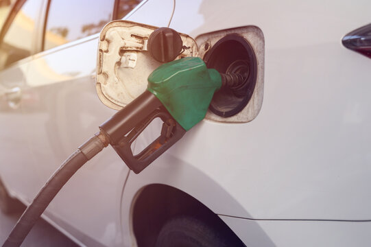 A close-up image of a gas station attendant's hand holding a fuel dispenser.	
