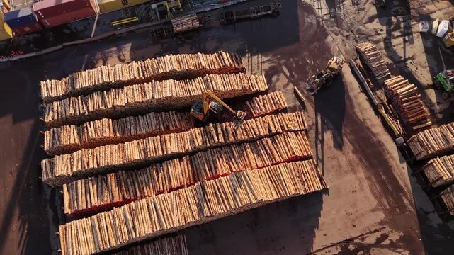 Excavator moving logs on timber stacks at Wellington port, Top down aerial view drone shot