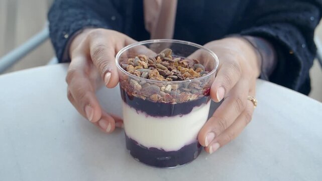 Person Holding a Layered Yogurt Parfait with Granola