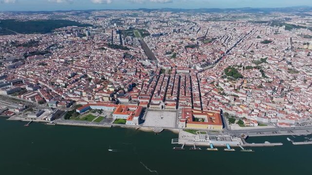 Breathtaking aerial footage of Lisbon&rsquo;s iconic Praca do Comercio and Rua Augusta Arch at midday. Drone glides above historic squares, red-tiled rooftops, and the Tagus River on a clear, sunny day.