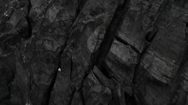 extreme close up aerial detail revealing the deep fissures, jagged fractures, and dark geological textures of the rocky moraine in Pakistan's Karimabad Glacier Valley