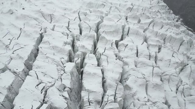 Top-down aerial view detailing the deep parallel fractures and sheer icy chasms cutting through Passu Cones Glacier in Pakistan