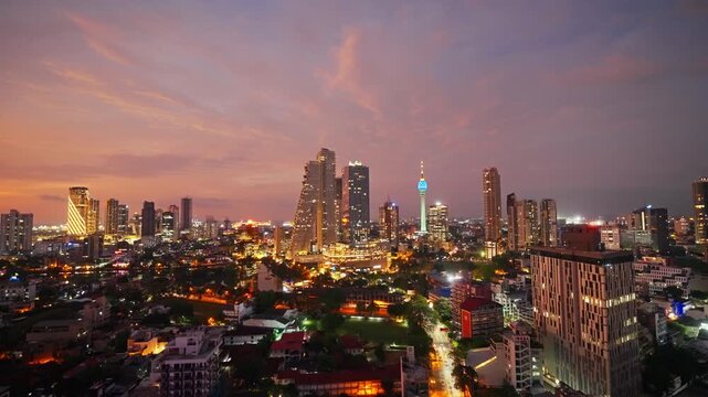 Time lapse from dusk into night over Colombo as the sky darkens and thousands of city lights ignite around the glowing Lotus Tower and skyscrapers of Sri Lanka's vibrant coastal capital.