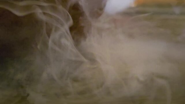 Close-up of pale ink or smoke drifting in dark water, forming soft swirling patterns, cloudy motion, and atmospheric abstract texture for background, overlay, or cinematic visual effects.