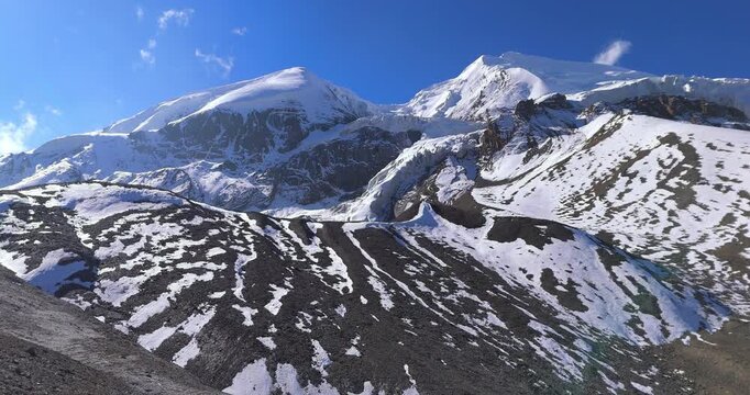 Thorong La Pass, Annapurna Circuit, Manang, Nepal, drone aerial shot of dramatic snow-capped Himalayan mountain peaks and icy slopes under a clear blue sky