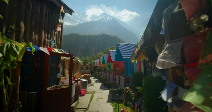 Annapurna Circuit, Manang, Nepal, a path lined with colorful teahouses and lodges in a mountain village beneath snow-capped Himalayan peaks.