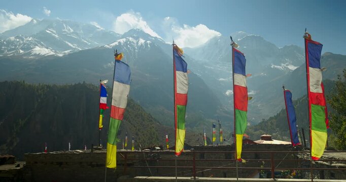 Annapurna Circuit, Manang, Nepal, Colorful tall Buddhist prayer flags framed by majestic snow-capped Himalayan mountains