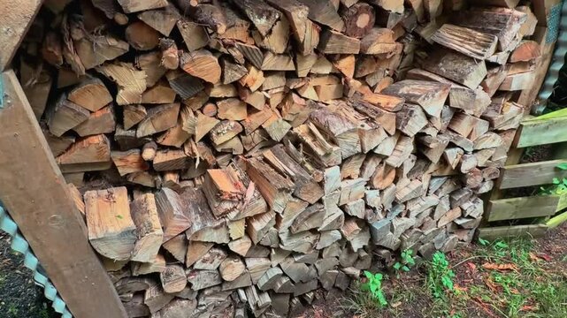 A neatly stacked pile of firewood sits in a peaceful rural setting in New Zealand. Natural timber prepared for heating, showcasing a traditional countryside lifestyle.
