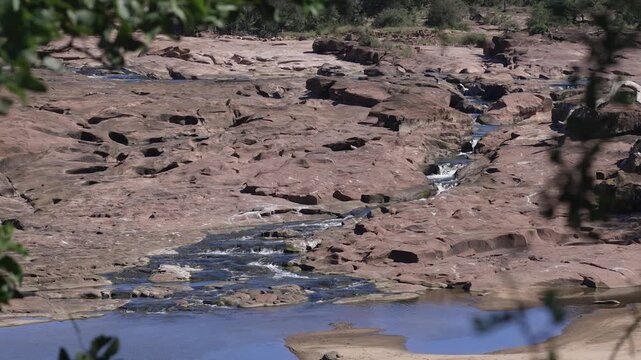 Small stream trickles through red sandstone riverbed rock, nature