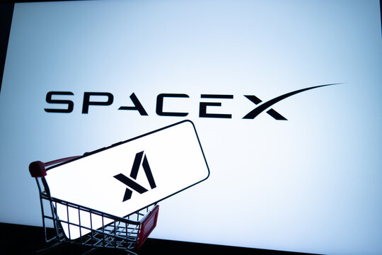 Phone showing xAI logo in a shopping cart against SpaceX logo.