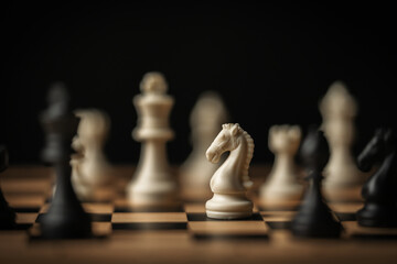 white chess knight in focus on a board with other pieces blurred on black background © geargodz