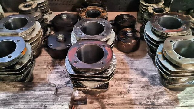 Collection of Used 2-Stroke Vespa Scooter Cylinder Blocks and Heads in a Garage