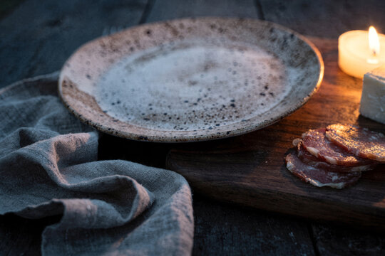 Rustic Ceramic Plate with Candlelight and Cured Meat Board