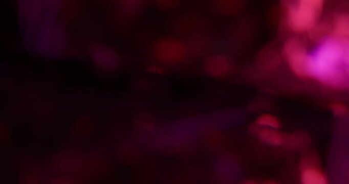Bokeh light. Pink glitter texture. Vibrant purple color lens flare bright optical glisten reflection on abstract illuminated black background.