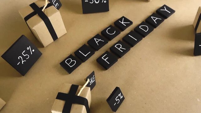 Camera gliding over a handcrafted promotional scene for Black Friday, showing gift boxes and various sale percentages written on black tiles, all set on a light brown paper background