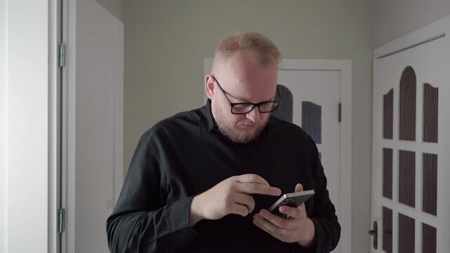 Middle-aged man in glasses scrolls on his smartphone, then rubs his tired eye as discomfort from screen overuse builds.