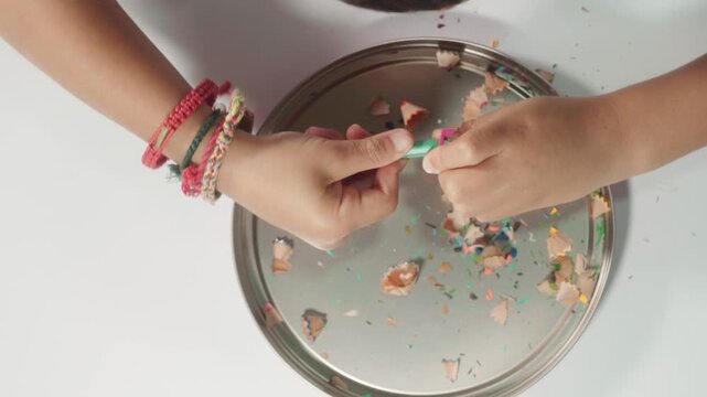 Young child independently sharpening a colored pencil, practicing hand strength, fine motor coordination, concentration, and personal responsibility during a creative activity.