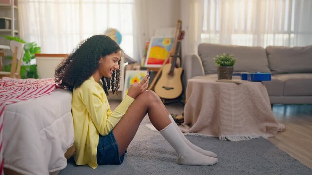 African American teenage girl using cellphone while sitting on the floor. 