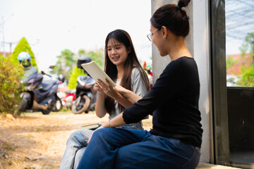 Fototapeta premium Two Asian girls studying together at outdoor cafe
