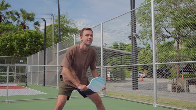 Athletic young sportsman playing pickleball during an outdoor match. 