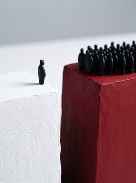 Single figure standing on cliff opposite crowd representing individuality and choice
