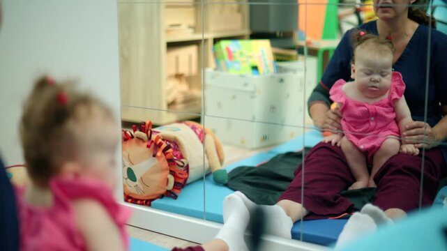 Baby girl with Down syndrome sitting on a therapist's lap, working on early intervention and development in a clinic