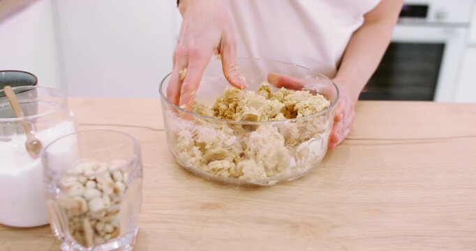 Kitchen work. Kneading dough. Female baker hand mixing butter ingredient with flour in glass bowl preparing tasty cookies at home.
