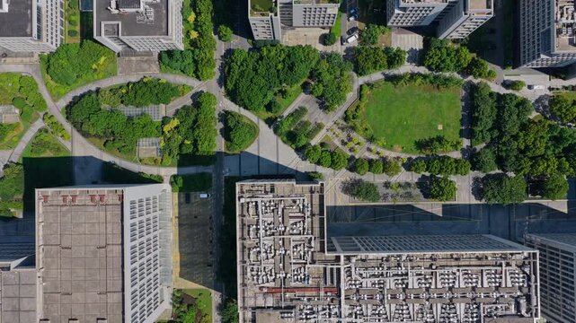 Drone moving forward over green buildings and a landscaped campus