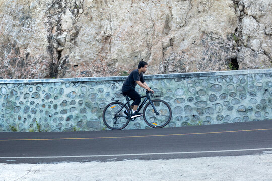 Man Cycling Along a Stone Wall Road