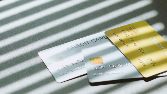 Personal finance management, group of credit cards on table under Venetian blind shadow. debt business concept idea.