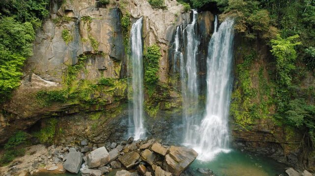 Nauyaca Waterfall plunges into rocky canyon surrounded by dense green rainforest