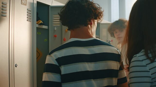 Teenage Boy Packing Things at Open Locker When Two Classmates Approach. One Aggressive Girl Suddenly Snatches Notebook Out of Hands and Starts Mocking. Concept of Bullying, Personal Space Violation.