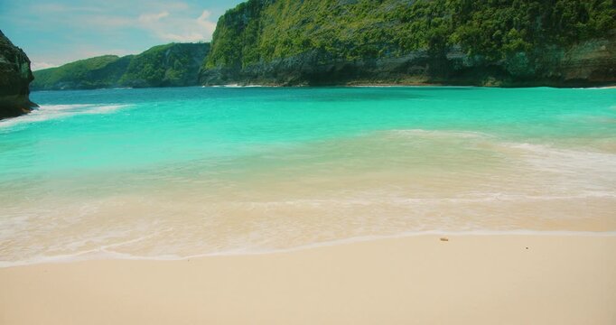 Empty stretch of white sand beach with turquoise ocean waves at Nusa Penida Bali