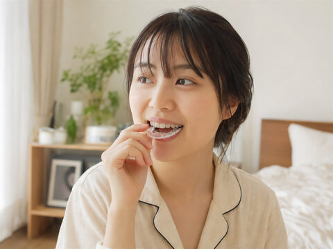 朝起きて透明マウスピースを外す女性 朝の生活シーン
