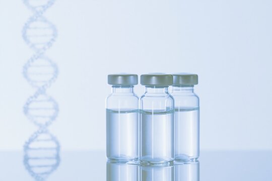 Three sealed glass vials with liquid on a reflective surface beside a particle DNA helix, featuring a clean and futuristic aesthetic for biotechnology research