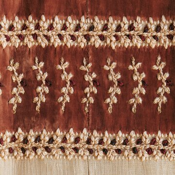 Red velvet fabric with embroidered vine patterns and a mended seam, featuring tactile silk threads for Jewish holiday packaging and product mockups