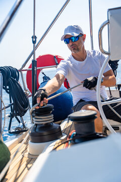 Experienced sailor trimming a sailing line on a modern yacht during an offshore passage. Seamanship, active boat handling, navigation skills and confident cruising under sail.