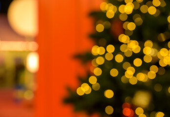 Fototapeta premium Abstract blurred Christmas tree with golden bokeh lights and red background