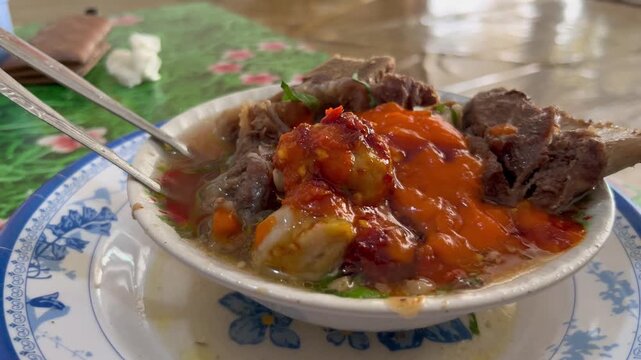 Indonesian spicy meatball soup or bakso iga served with chili sauce in a bowl⁠
