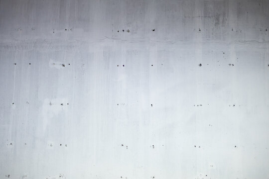 Minimalist light grey concrete surface showcasing raw cement texture and small formwork holes in industrial style.